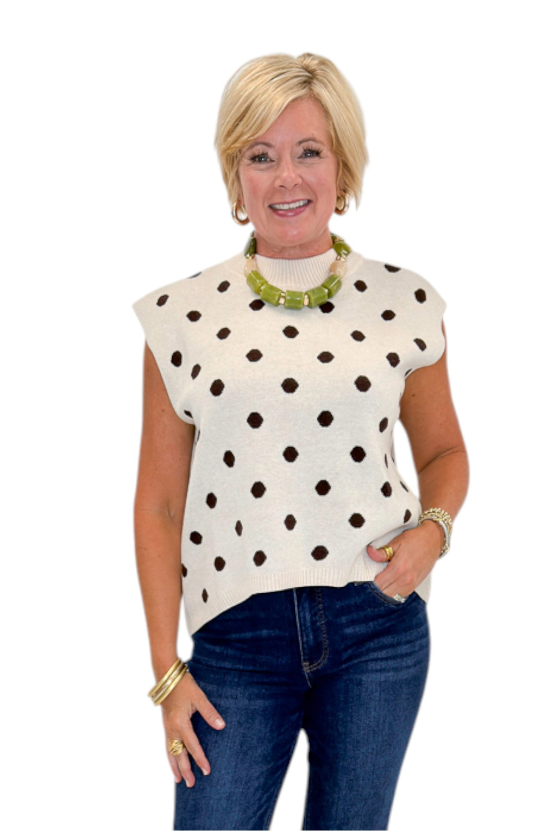 Front view of woman wearing Swagger Boutique’s Oatmeal &amp; Brown Polka Dot Sleeveless Sweater by Entro with jeans against white studio background.