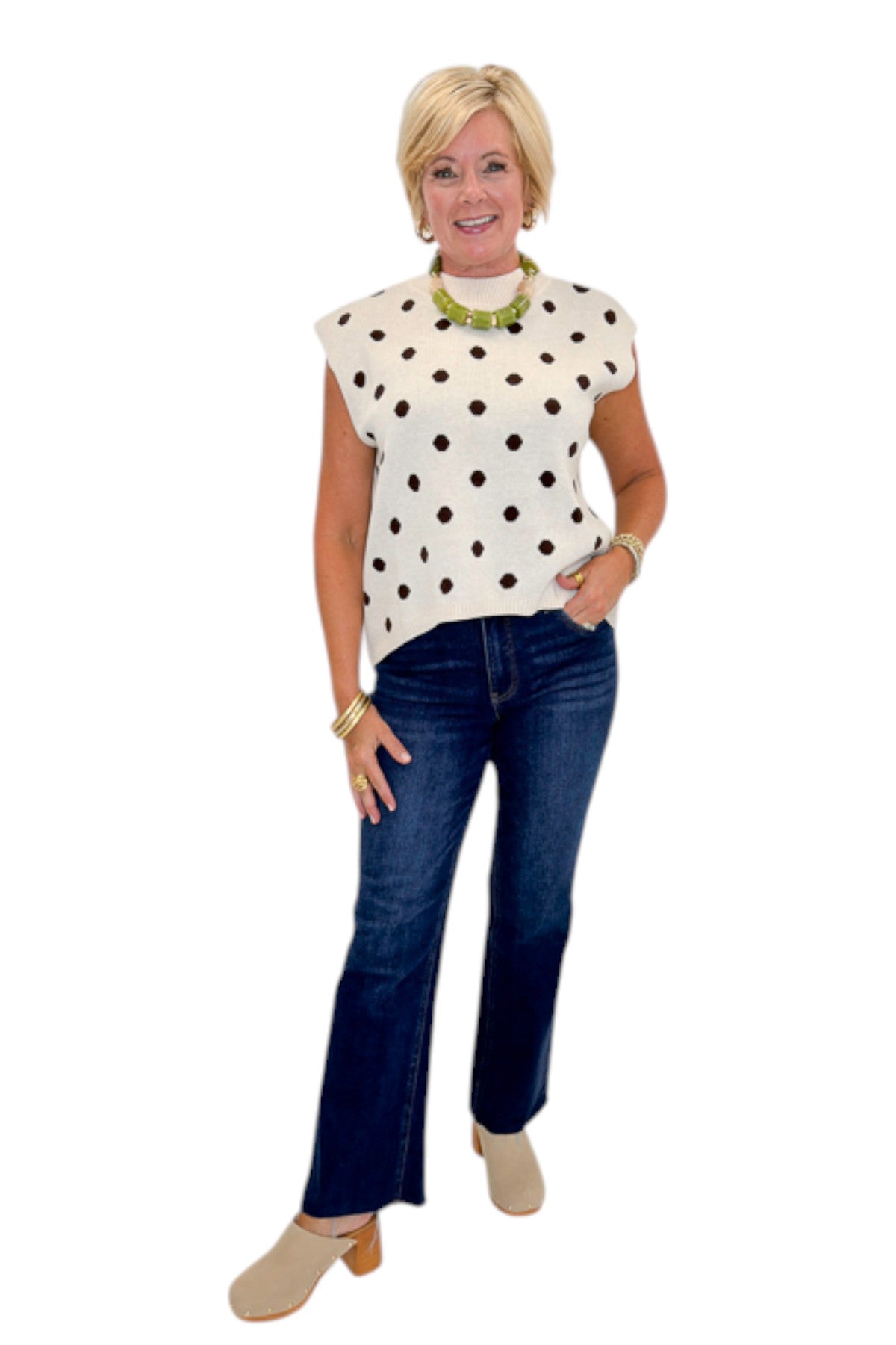Front view of woman wearing Swagger Boutique’s Oatmeal &amp; Brown Polka Dot Sleeveless Sweater by Entro with jeans against white studio background.