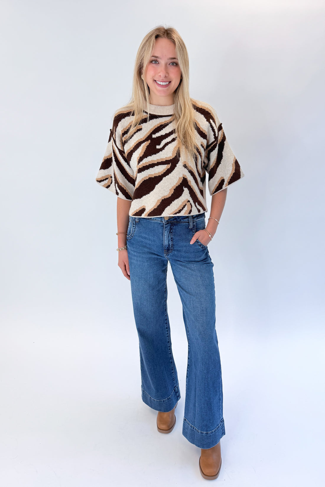Front view of woman wearing Swagger Boutique’s Oatmeal &amp; Brown Zebra Short Sleeve Sweater by Entro with jeans against white studio background.