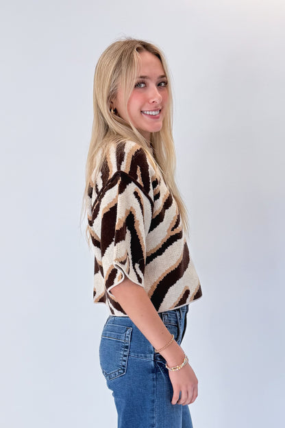 Side view of woman wearing Swagger Boutique’s Oatmeal &amp; Brown Zebra Short Sleeve Sweater by Entro with jeans against white studio background.