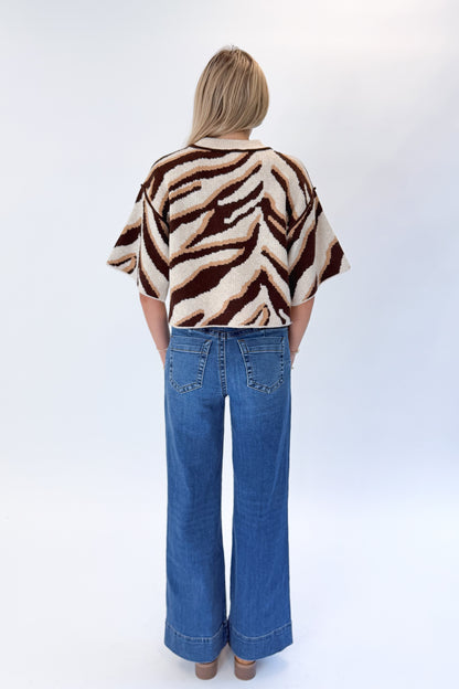 Back view of woman wearing Swagger Boutique’s Oatmeal &amp; Brown Zebra Short Sleeve Sweater by Entro with jeans against white studio background.