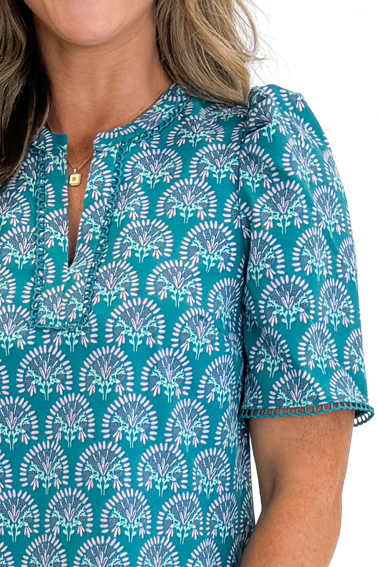 Front detail view of woman wearing Swagger Boutique’s Ocean Sunshower Flora Adelyn Top by Mary Square with jeans against white studio background.