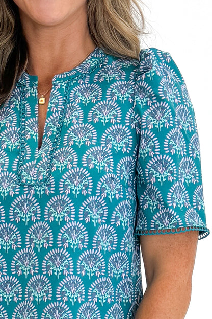Front detail view of woman wearing Swagger Boutique’s Ocean Sunshower Flora Adelyn Top by Mary Square with jeans against white studio background.