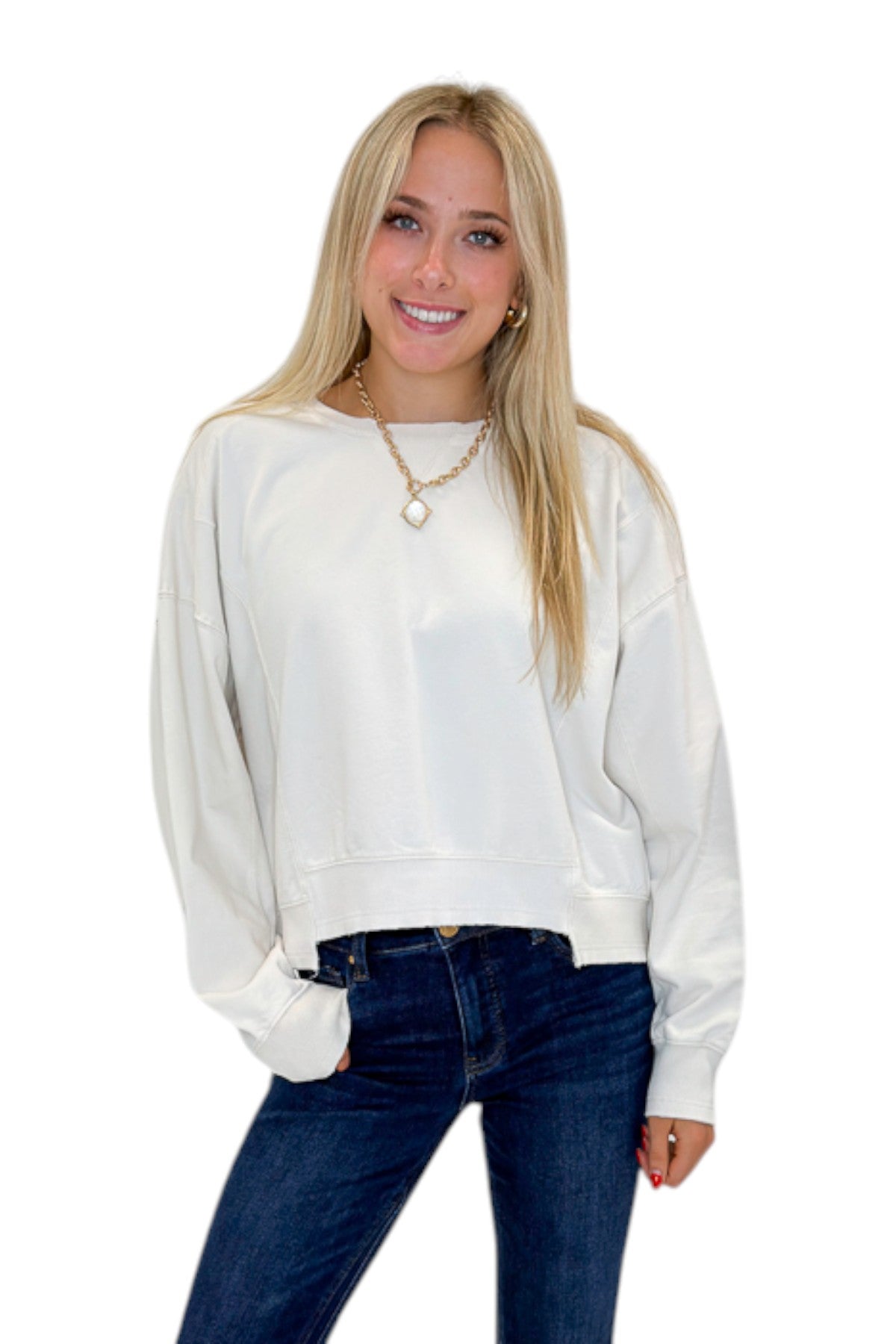 Front view of woman wearing Swagger Boutique’s Off White Ribbed Detail Sweatshirt with jeans against white studio background.