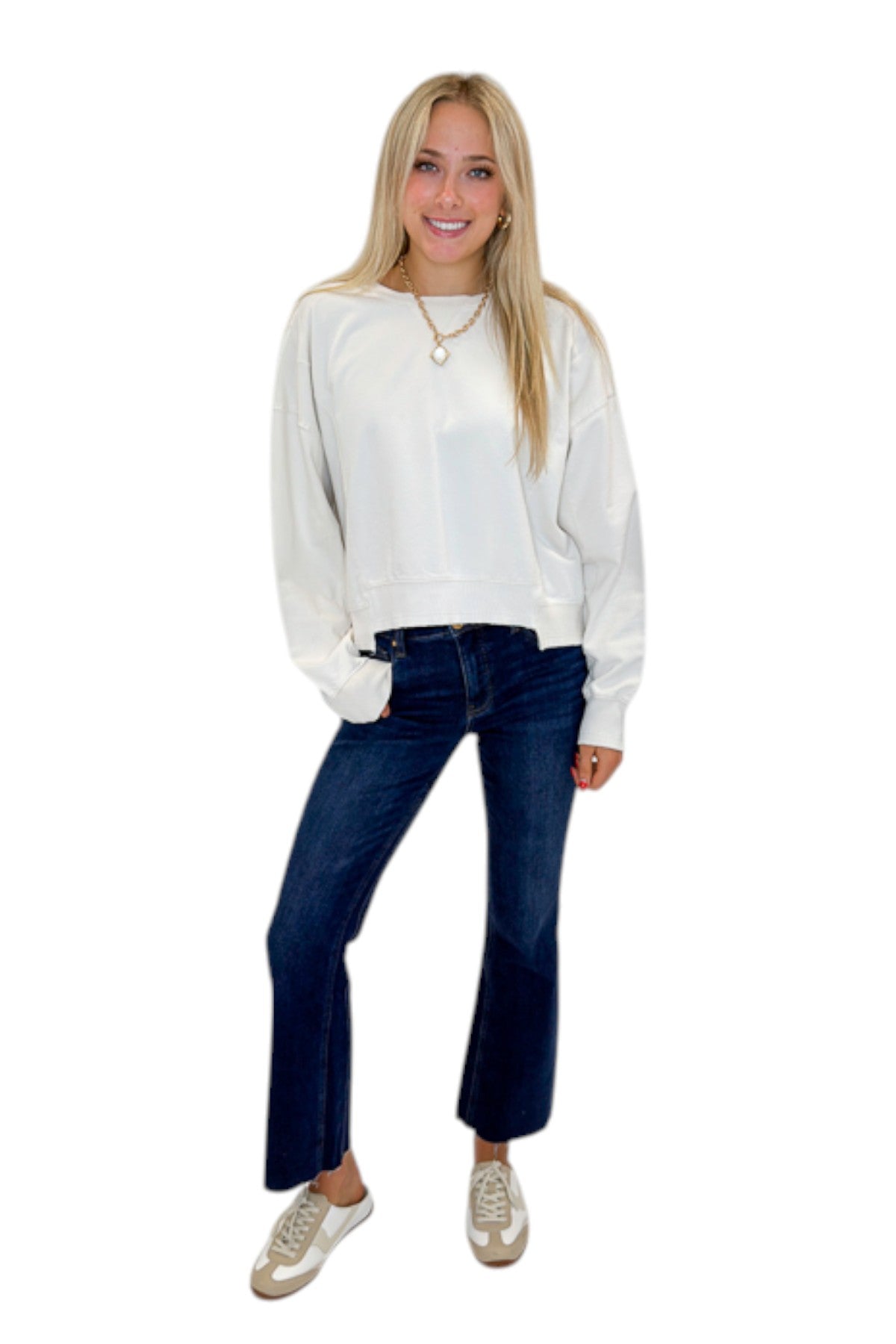 Front view of woman wearing Swagger Boutique’s Off White Ribbed Detail Sweatshirt with jeans against white studio background.