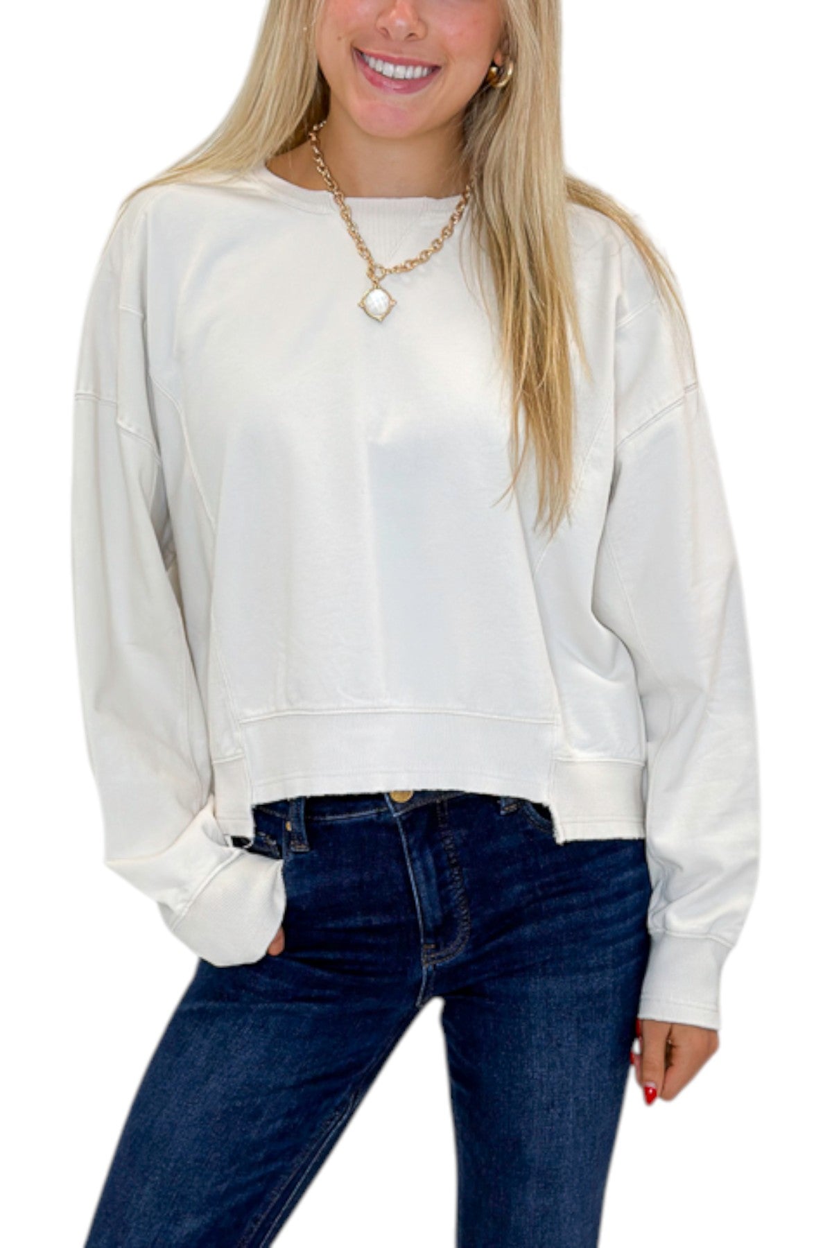 Front detail view of woman wearing Swagger Boutique’s Off White Ribbed Detail Sweatshirt with jeans against white studio background.