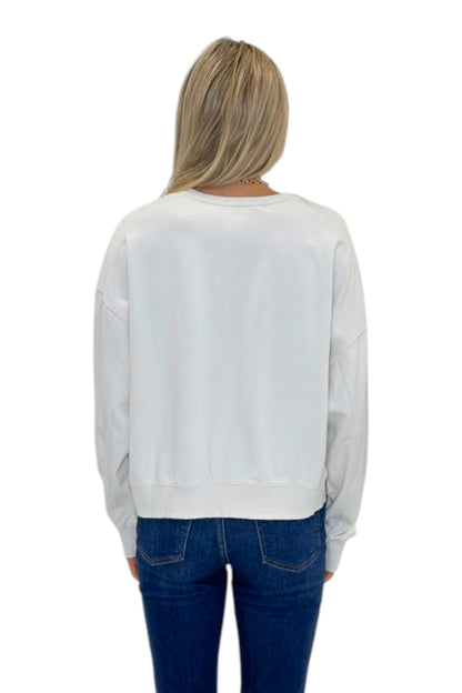 Back view of woman wearing Swagger Boutique’s Off White Ribbed Detail Sweatshirt with jeans against white studio background.