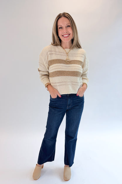 Front view of woman wearing Swagger Boutique’s Off White, Beige and Metallic Stripe Sweater by Molly Bracken with jeans against white studio background.
