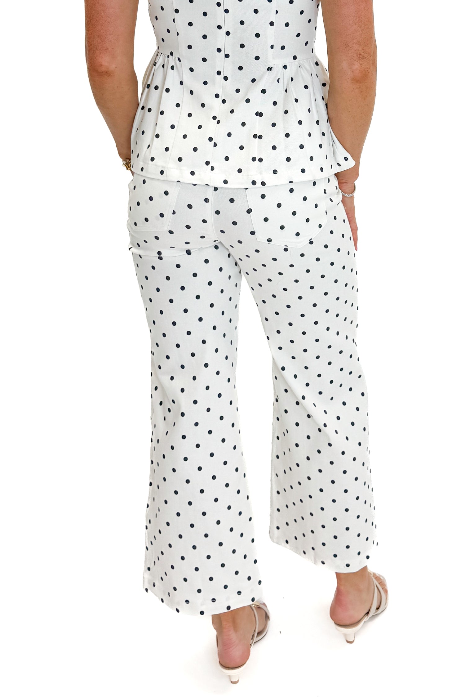 Back view of woman wearing Swagger Boutique’s Off White &amp; Navy Polka Dot Jeans by Entro with matching top against white studio background.