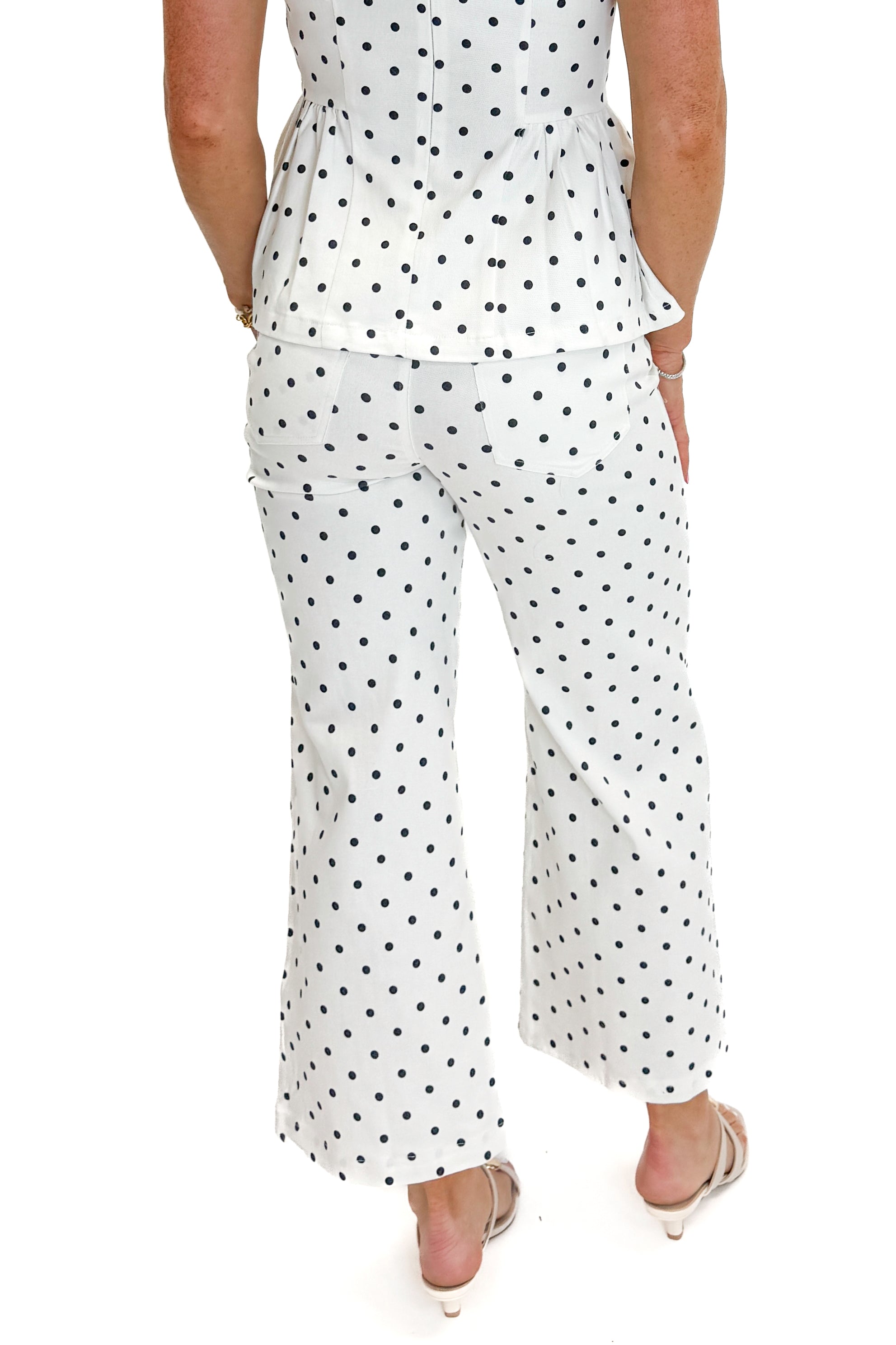 Back view of woman wearing Swagger Boutique’s Off White &amp; Navy Polka Dot Jeans by Entro with matching top against white studio background.