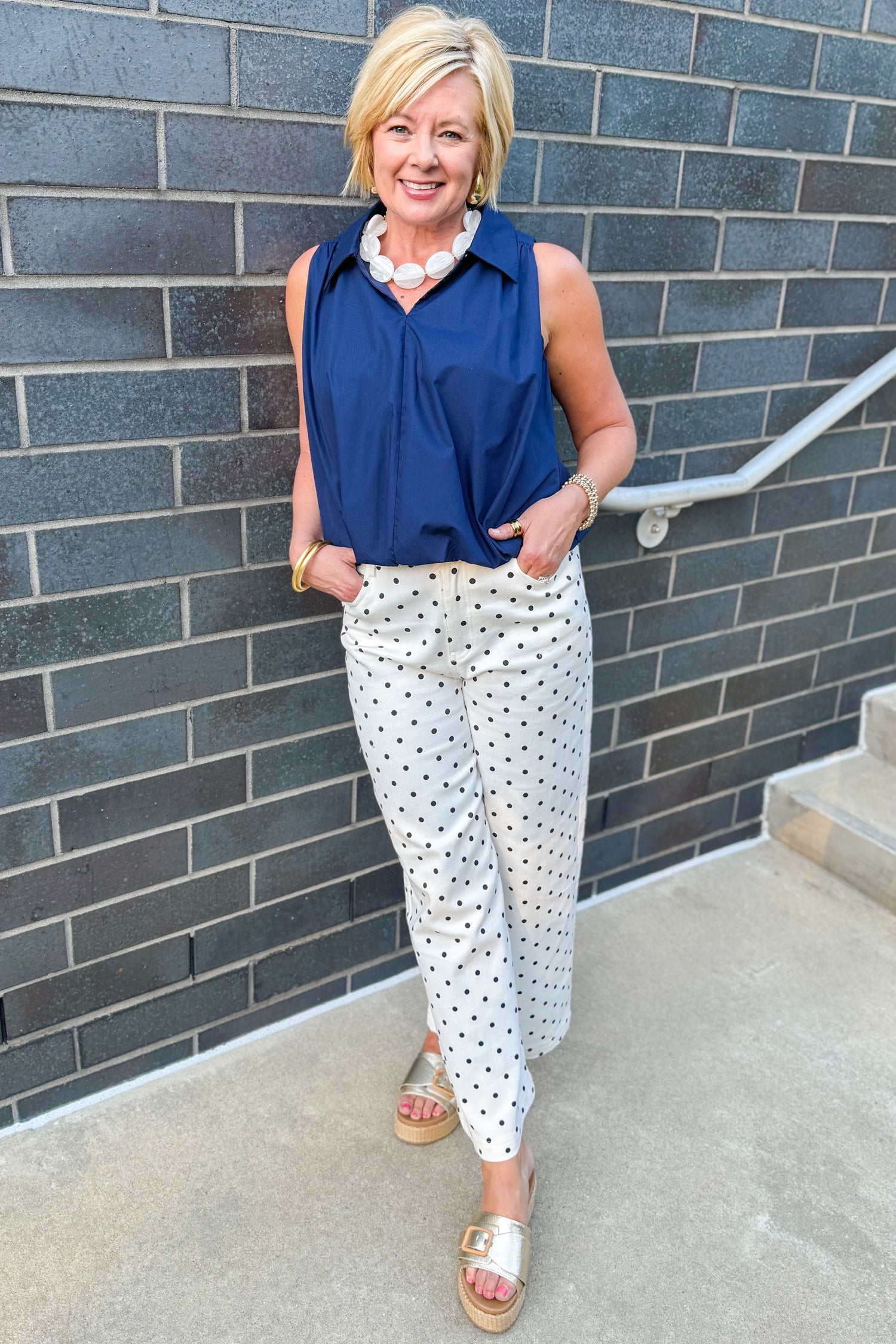 Front view of woman wearing Swagger Boutique’s Off White &amp; Navy Polka Dot Jeans by Entro with navy top against white studio background.