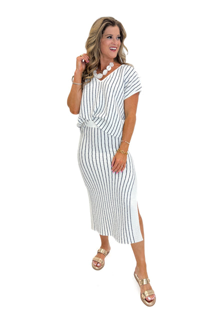 Front view of woman wearing Swagger Boutique’s Off White &amp; Navy Striped V-neck Top with Off White &amp; Navy Striped Midi Skirt With Slit against white studio background.