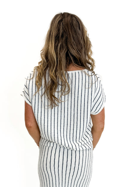 Back view of woman wearing Swagger Boutique’s Off White &amp; Navy Striped Midi Skirt With Slit and matching top against white studio background.