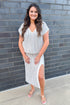 Front view of woman wearing Swagger Boutique’s Off White & Navy Striped V-neck Top with Off White & Navy Striped Midi Skirt With Slit outside against a brick wall.
