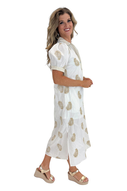 Side view of woman wearing Swagger Boutique’s Off White &amp; Taupe Embroidered Midi Dress with sandals against white studio background.