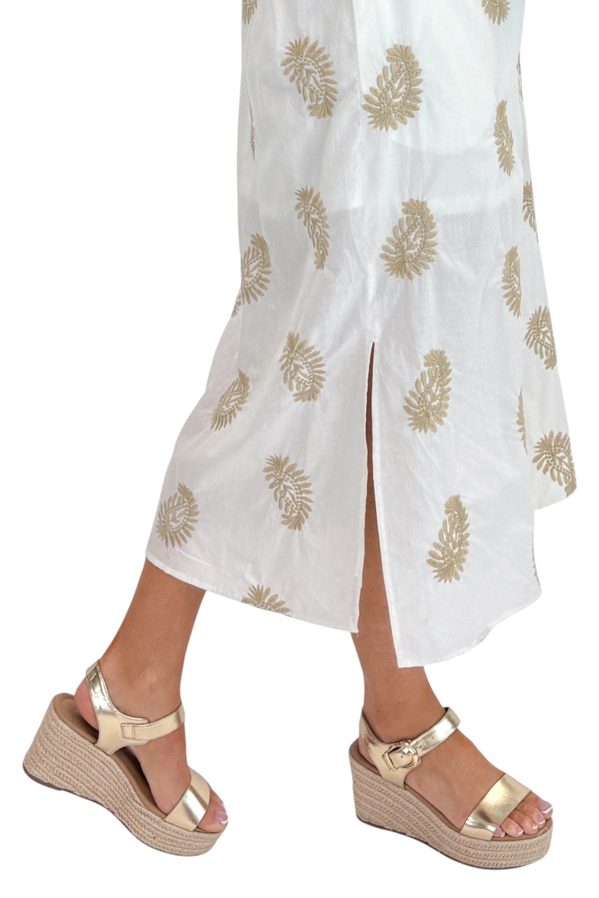 Side detail view of woman wearing Swagger Boutique’s Off White &amp; Taupe Embroidered Midi Dress with sandals against white studio background.