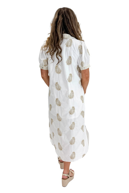 Back view of woman wearing Swagger Boutique’s Off White &amp; Taupe Embroidered Midi Dress with sandals against white studio background.