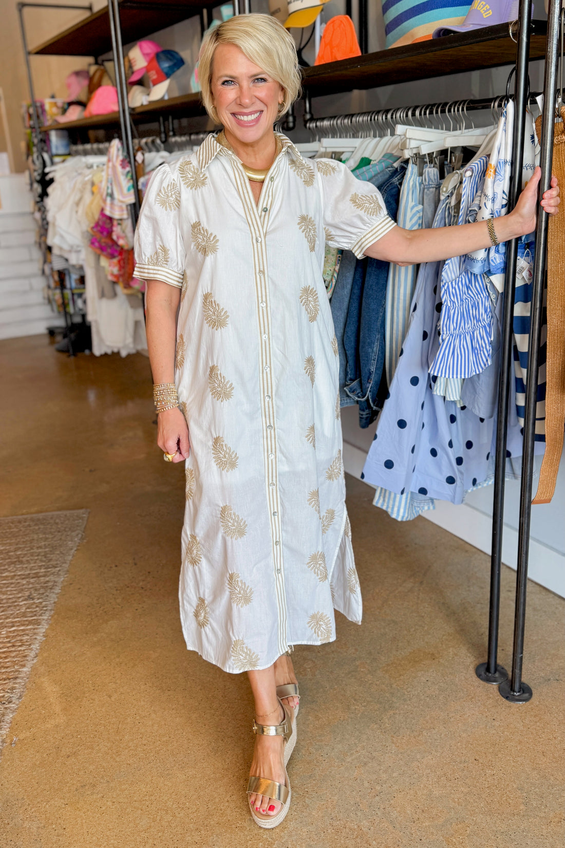 Front view of woman wearing Swagger Boutique’s Off White &amp; Taupe Embroidered Midi Dress with sandals standing in the store.