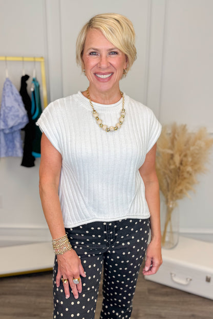 front view of woman wearing a short sleeve white sweater top. 