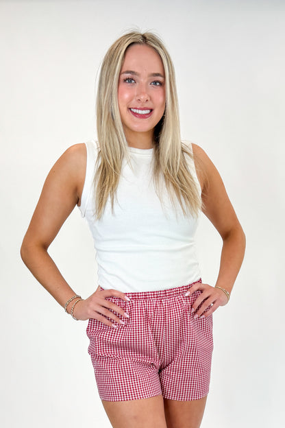 Front view of woman wearing Swagger Boutique’s Red Gingham Shorts with Off White Round Hem Ribbed Tank against white studio background.