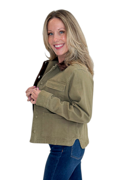 Side view of woman wearing Swagger Boutique’s Olive Barn Jacket With Corduroy Collar with jeans against white studio background.