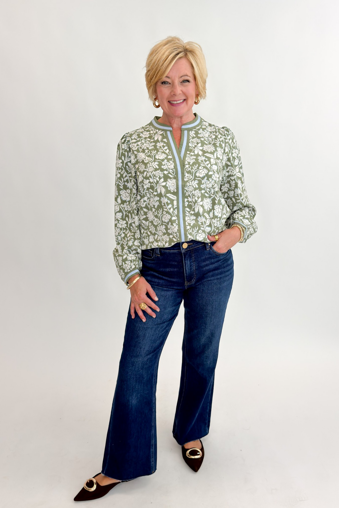 Front view of woman wearing Swagger Boutique’s Olive Floral V-Neck Top with jeans against white studio background.