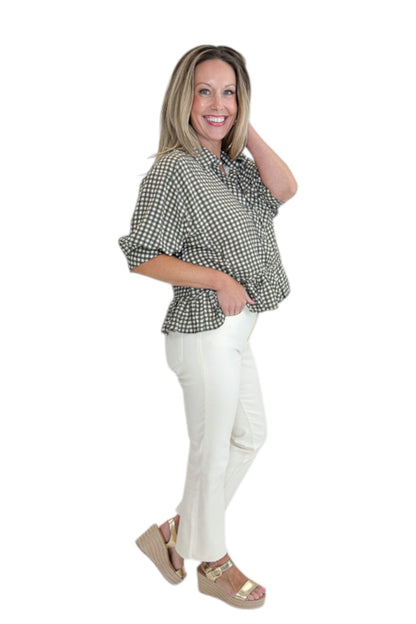 Side view of woman wearing Swagger Boutique’s Olive Gingham Peplum Top by Entro with jeans against white studio background.