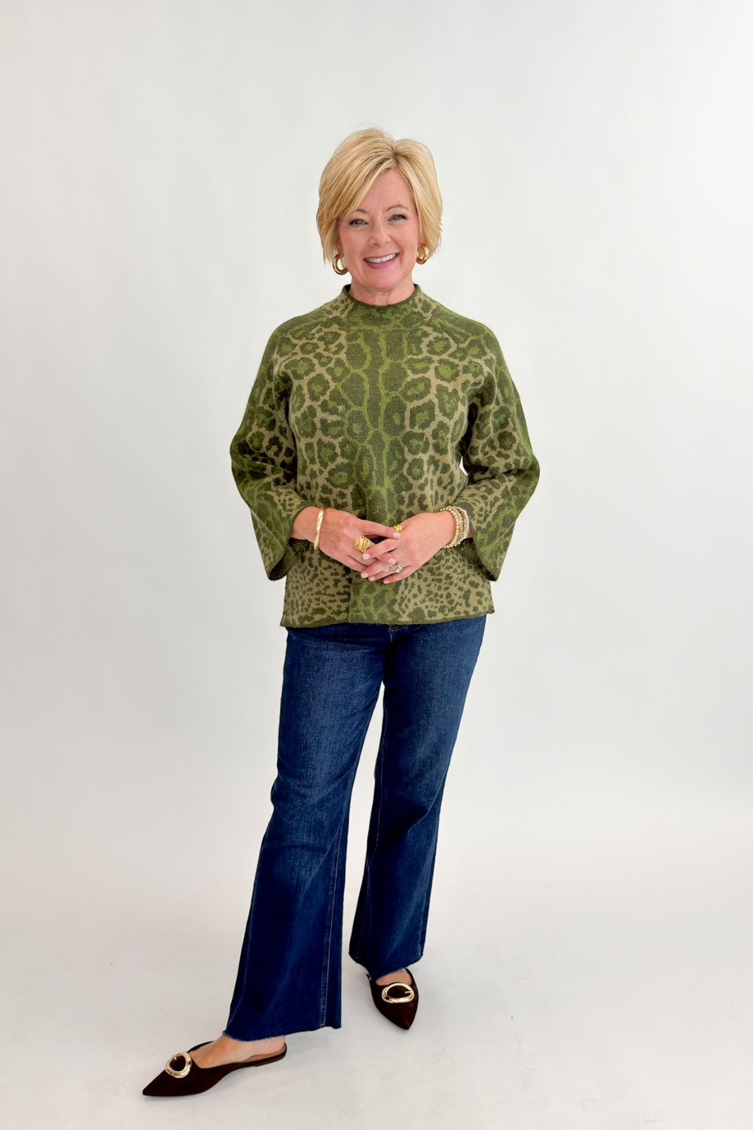 Front view of woman wearing Swagger Boutique’s Olive Leopard Print Mock Neck Sweater by Entro with jeans against white studio background.
