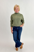 Front view of woman wearing Swagger Boutique’s Olive Mock Neck Sweater by Entro with jeans against white studio background.