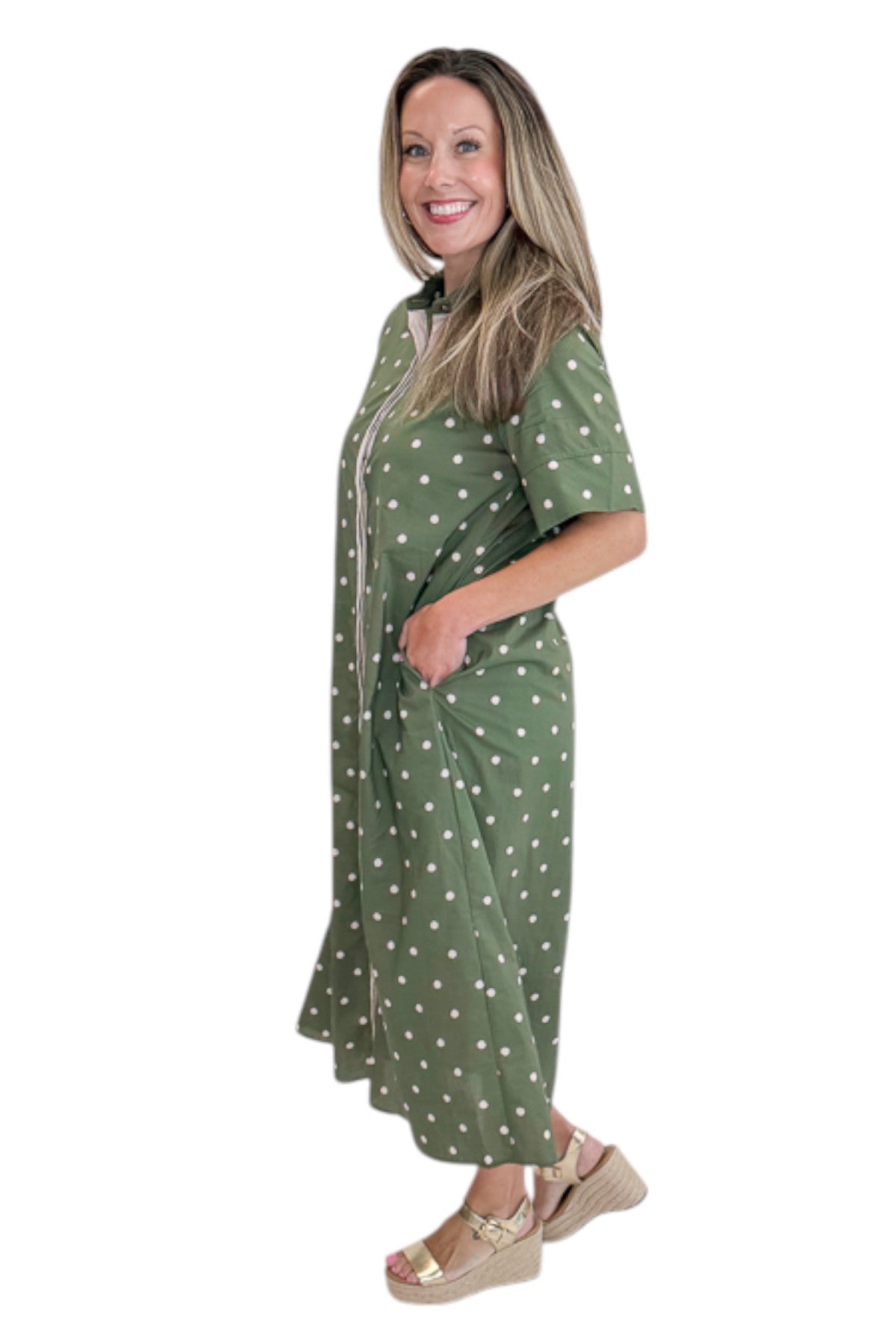 Side view of woman wearing Swagger Boutique’s Olive Polka Dot Midi Dress by Entro with sandals against white studio background.
