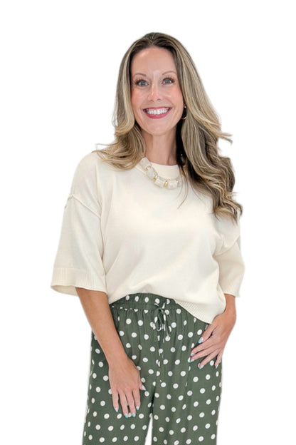Front view of woman wearing Swagger Boutique’s Cream 3/4 Sleeve Lightweight Sweater by Entro with Olive Polka Dot Stripe Trim Pants by Entro against white studio background.