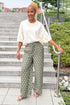 Front view of woman wearing Swagger Boutique’s Cream 3/4 Sleeve Lightweight Sweater by Entro with Olive Polka Dot Stripe Trim Pants by Entro standing by a staircase outside.
