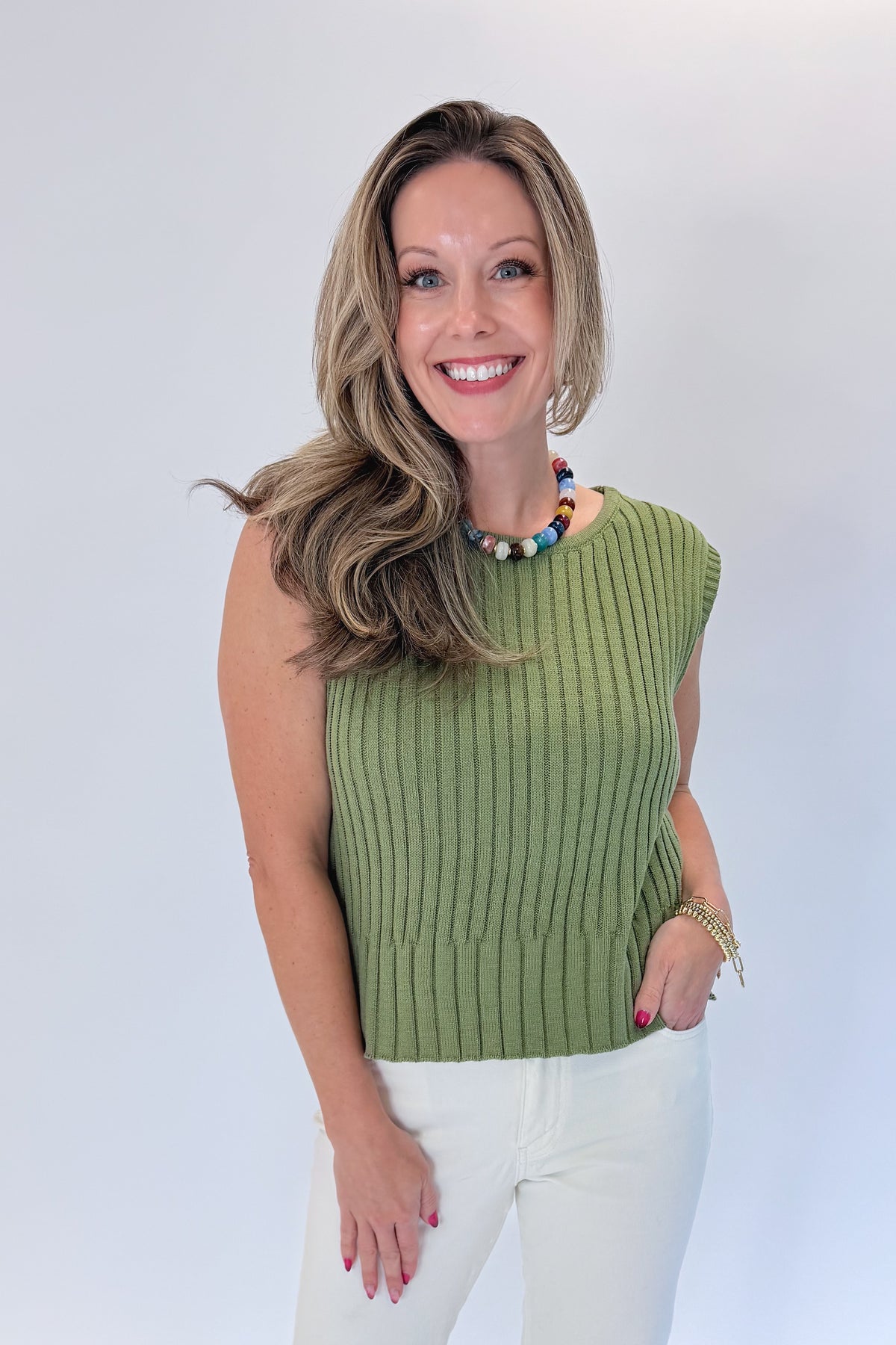 Front view of woman wearing Swagger Boutique’s Olive Ribbed Sleeveless Sweater with jeans against white studio background.