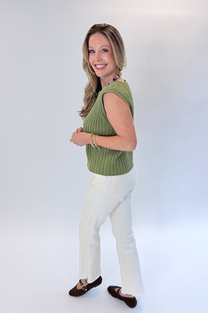 Side view of woman wearing Swagger Boutique’s Olive Ribbed Sleeveless Sweater with jeans against white studio background.
