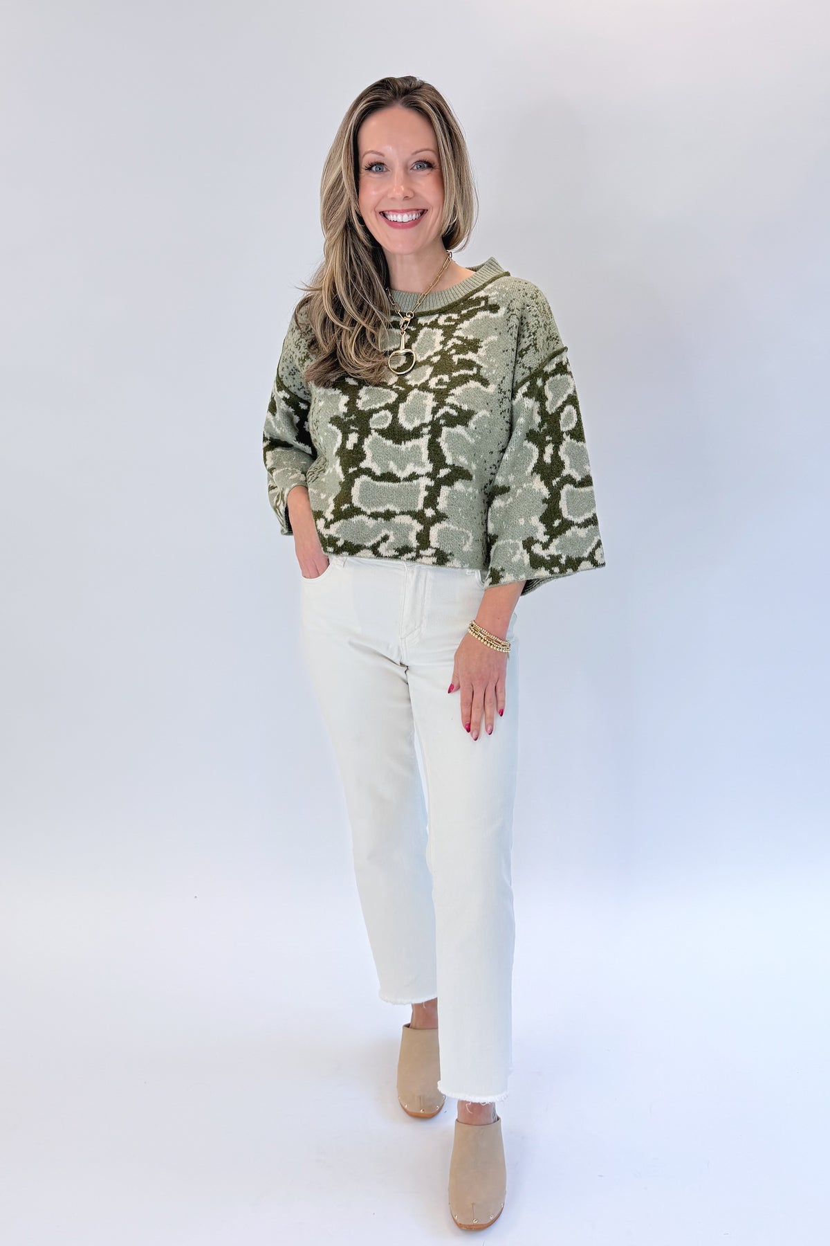 Front view of woman wearing Swagger Boutique’s Olive Snake Print Sweater by Entro with jeans against white studio background.