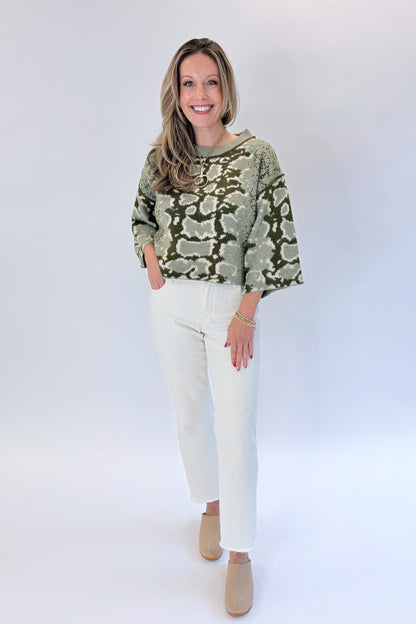 Front view of woman wearing Swagger Boutique’s Olive Snake Print Sweater by Entro with jeans against white studio background.