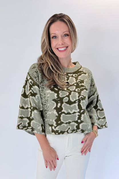 Front view of woman wearing Swagger Boutique’s Olive Snake Print Sweater by Entro with jeans against white studio background.