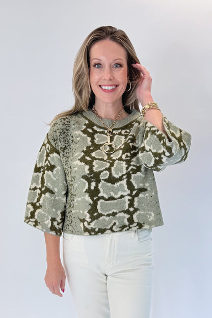 Front view of woman wearing Swagger Boutique’s Olive Snake Print Sweater by Entro with jeans against white studio background.