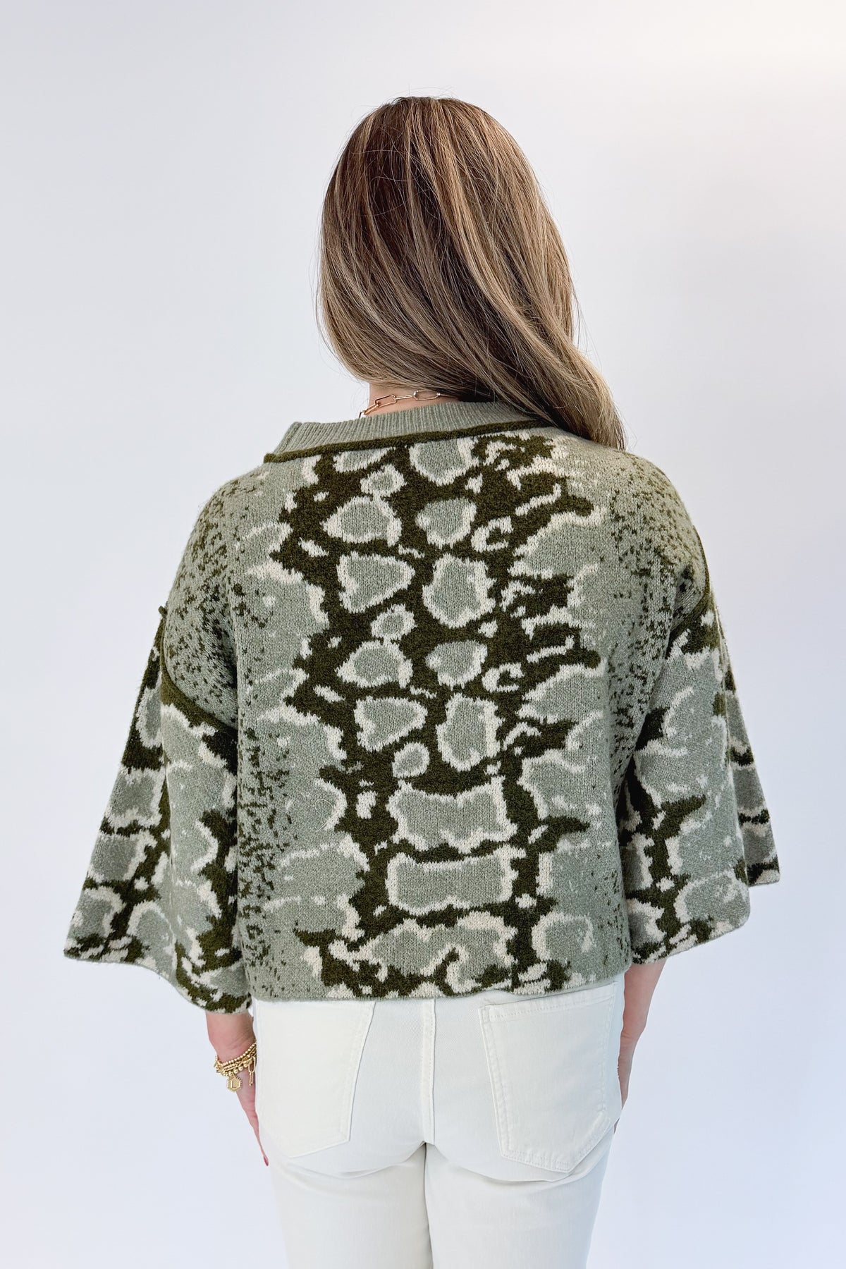 Back view of woman wearing Swagger Boutique’s Olive Snake Print Sweater by Entro with jeans against white studio background.