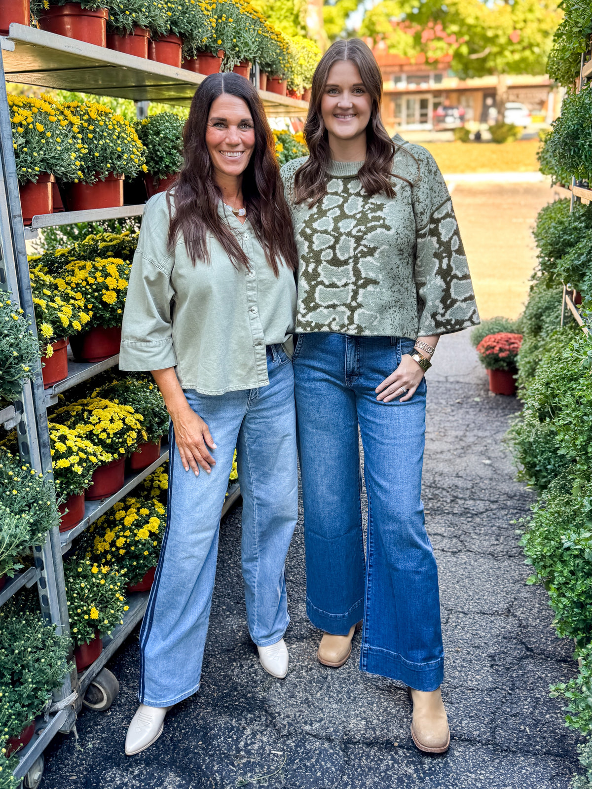 Front view of women wearing Swagger Boutique’s Olive Snake Print Sweater by Entro and Washed Olive 3/4 Sleeve Button Down Top with jeans at a garden center.