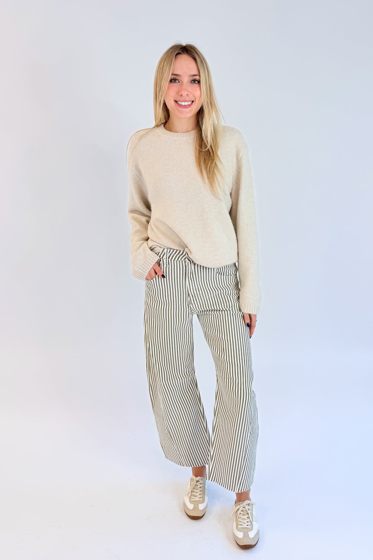Front view of woman wearing Swagger Boutique’s top with Olive Striped Barrel Jeans by Just Black Denim against white studio background.