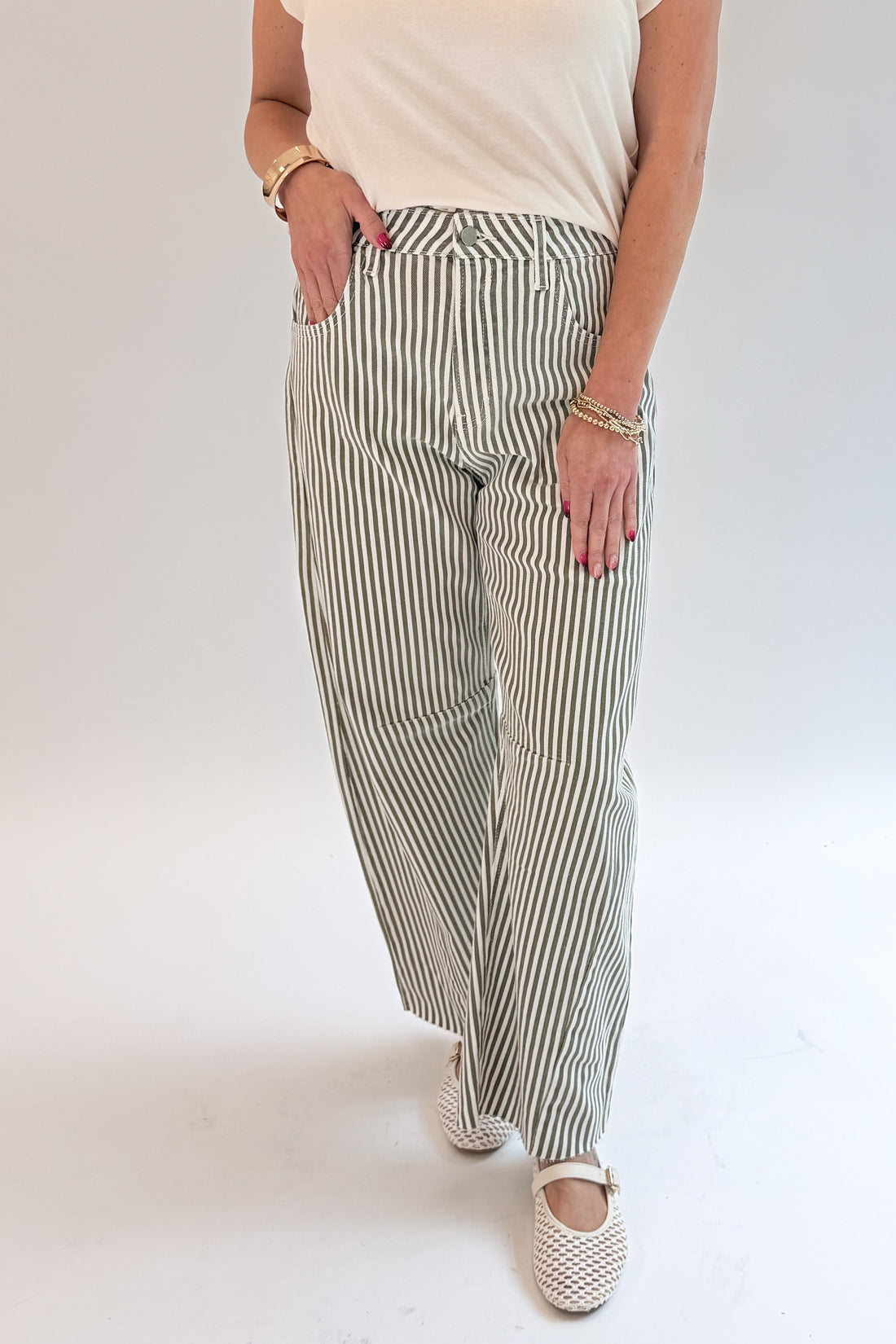 Front detail view of woman wearing Swagger Boutique’s top with Olive Striped Barrel Jeans by Just Black Denim against white studio background.