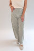 Front detail view of woman wearing Swagger Boutique’s top with Olive Striped Barrel Jeans by Just Black Denim against white studio background.