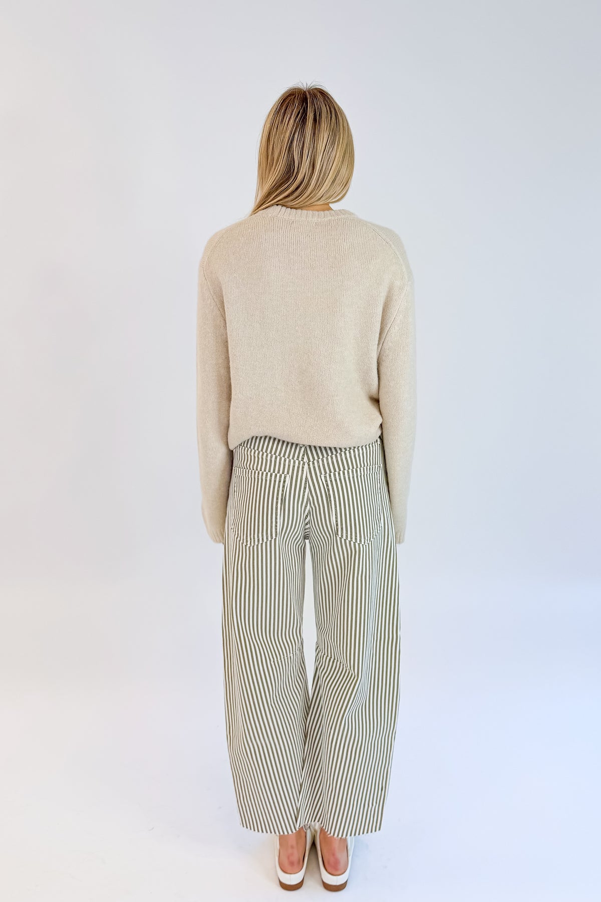 Back view of woman wearing Swagger Boutique’s top with Olive Striped Barrel Jeans by Just Black Denim against white studio background.