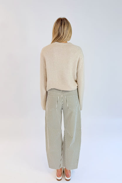 Back view of woman wearing Swagger Boutique’s top with Olive Striped Barrel Jeans by Just Black Denim against white studio background.