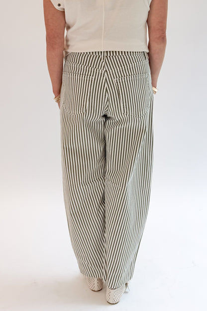 Back view of woman wearing Swagger Boutique’s top with Olive Striped Barrel Jeans by Just Black Denim against white studio background.