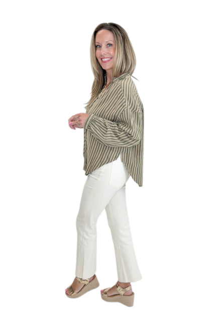 Side view of woman wearing Swagger Boutique’s Olive Striped Button Up Top with jeans against white studio background.