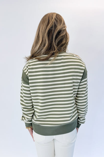 Back view of woman wearing Swagger Boutique’s Olive Striped Sweatshirt with jeans against white studio background.