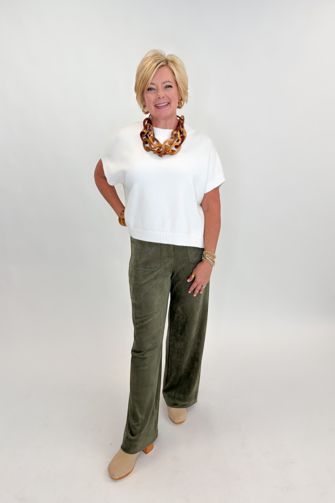 Front view of woman wearing Swagger Boutique’s sweater with Olive Suede Wide Leg Pants against white studio background.