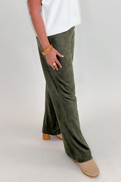 Side view of woman wearing Swagger Boutique’s sweater with Olive Suede Wide Leg Pants against white studio background.